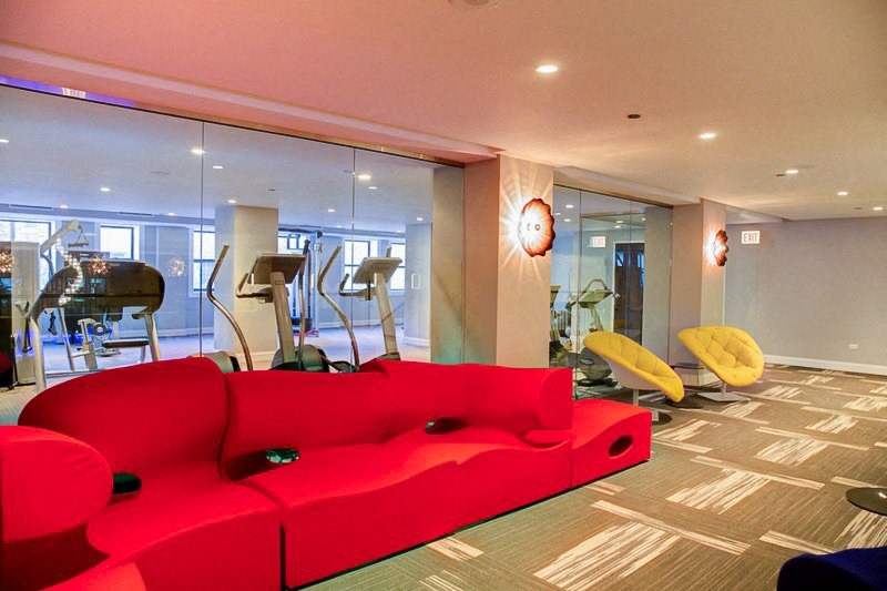 a living room with a red couch and exercise equipment