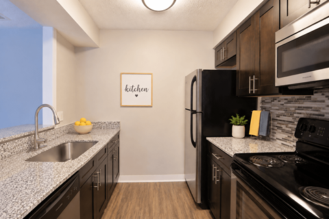 A kitchen with a fridge, stove, and sink.