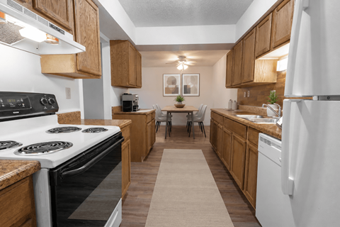 A kitchen with white appliances and wooden cabinets.
