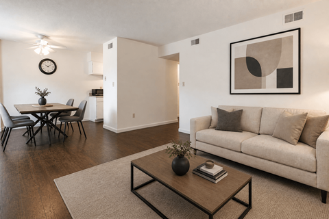 A living room with a couch, a dining table, and a painting on the wall.