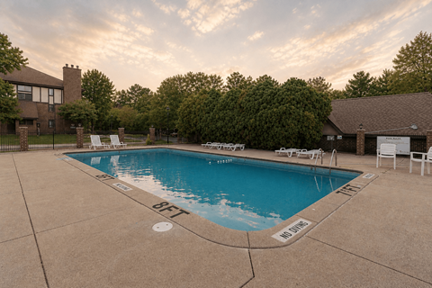 A large outdoor swimming pool surrounded by trees and a house.