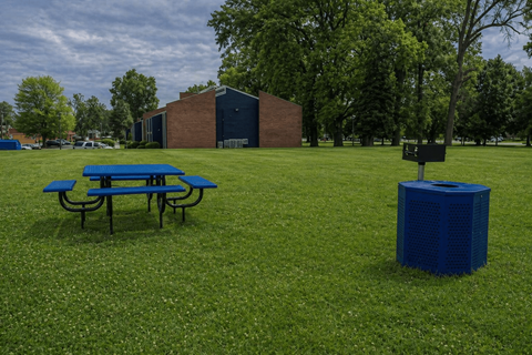 A blue picnic table sits on a grassy field.