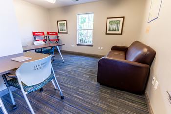 a study room with a leather couch and a table and chairs