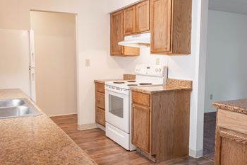 a kitchen with white appliances and wooden cabinets and a sink