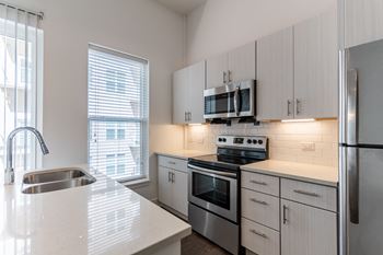 a luxury kitchen with white cabinets and stainless steel appliances at The Whit in Indianapolis, IN 46204