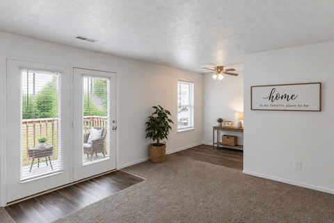 A room with a carpeted floor, a ceiling fan, and a framed picture that says "home" on the wall.