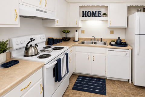 A white kitchen with a sign that says "HOME" on the wall.