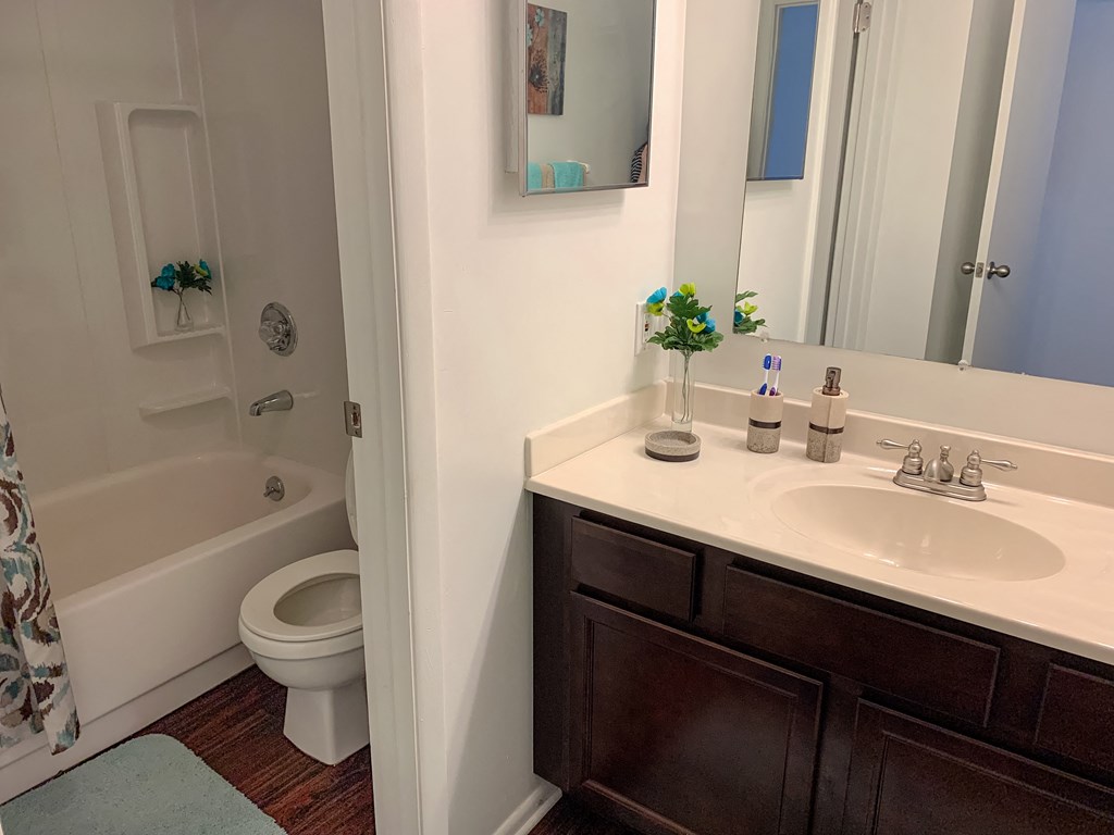 Modern bathroom with wood-style plank flooring at The Lodge Apartments in Indianapolis, IN