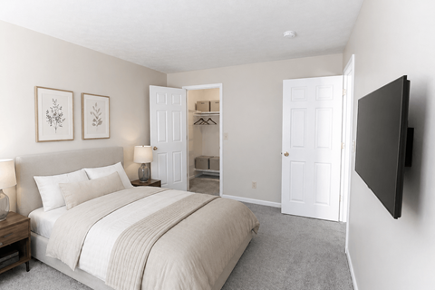 A bedroom with a large bed and a flat screen TV mounted on the wall.