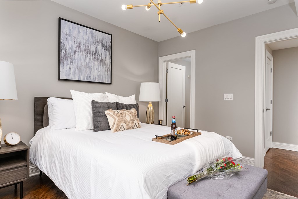 a bedroom with a white bed and a table with a bottle of wine