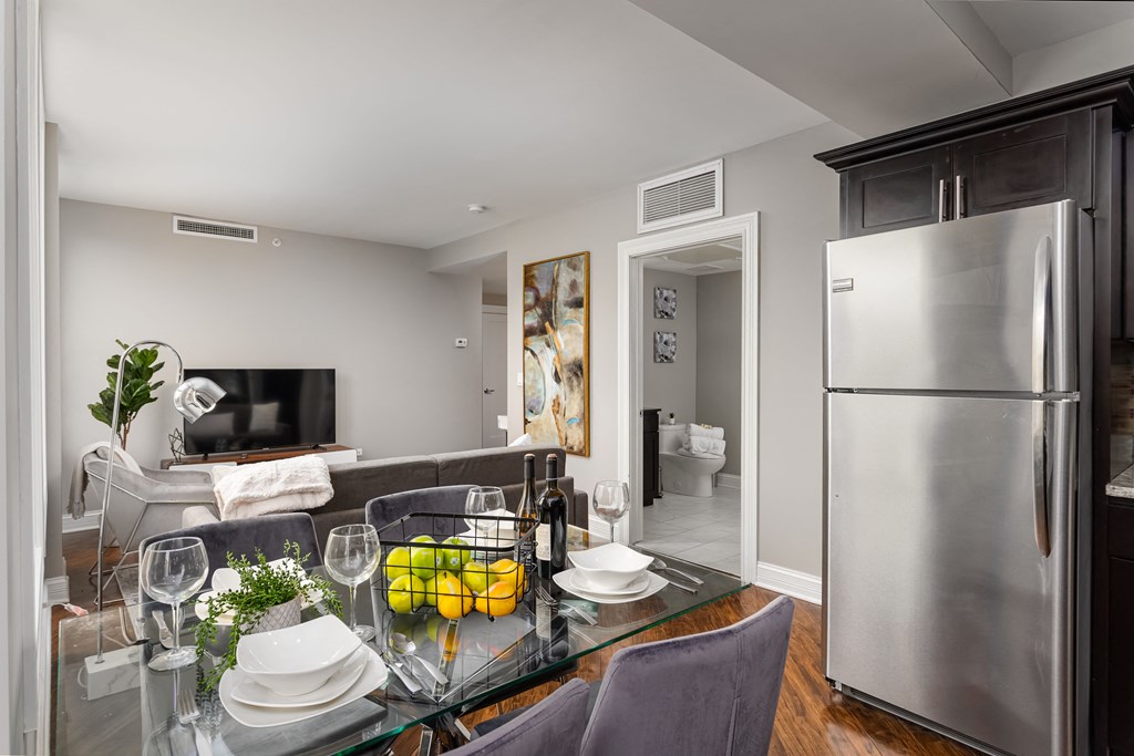 a kitchen and living room with a glass table and a refrigerator