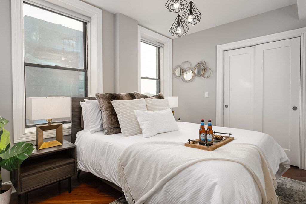 a bedroom with a white bed and two windows