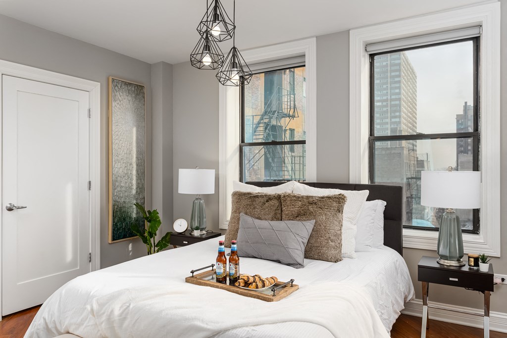 a bedroom with a large bed and two windows