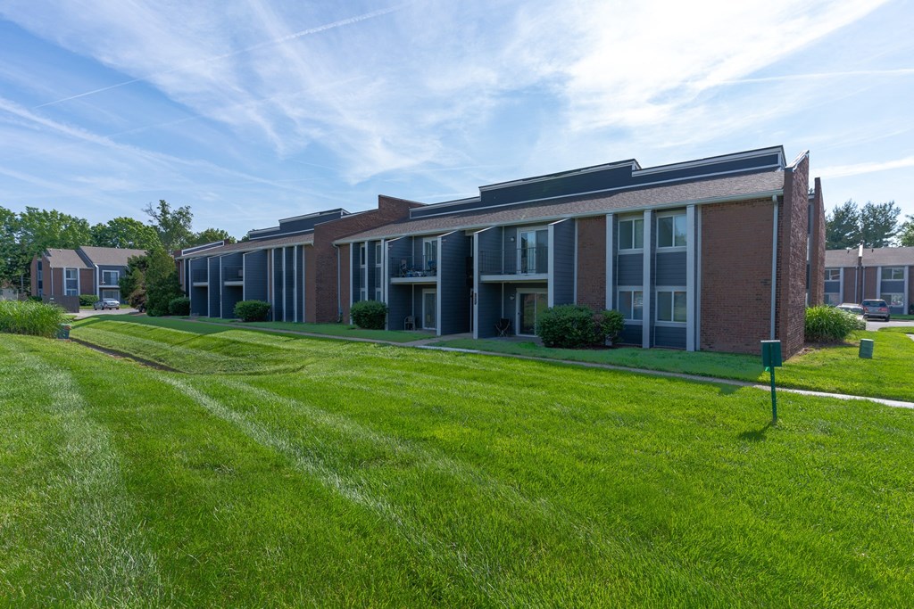 a large brick building with a green lawn in front of it