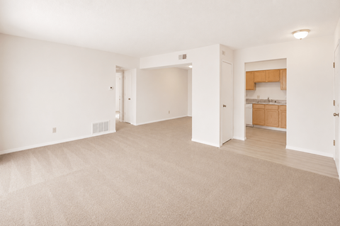 A large, empty room with a carpeted floor and white walls.