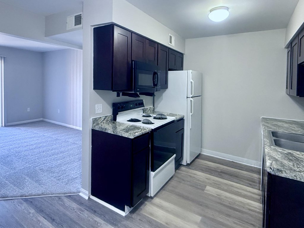 A kitchen with a black countertop and white appliances.