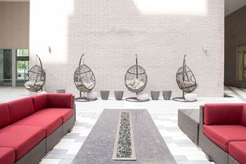 Lounge area with swings Courtyard with cozy fireplace and seating at The Whit in Indianapolis, IN 46204