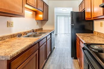 a kitchen with wood cabinets and granite counter tops and a black refrigerator
