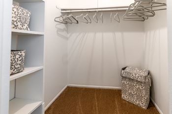 a walk in closet with white walls and shelves and a bag on the floor