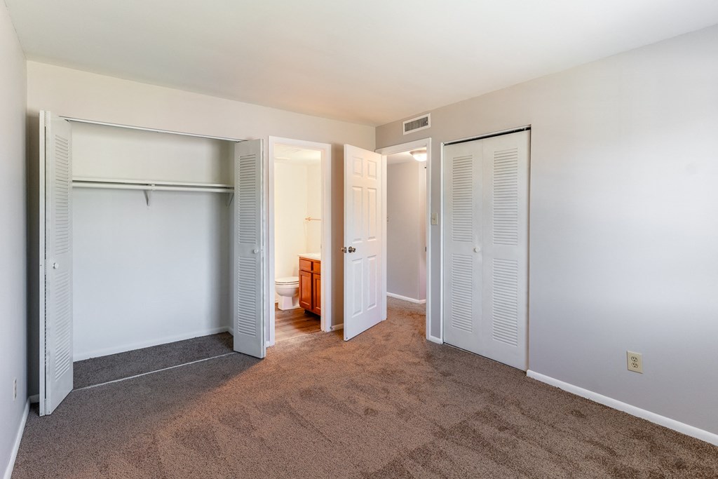 a spacious bedroom with closet doors and a bathroom at Pickwick Farms Apartments, Indianapolis, 46260