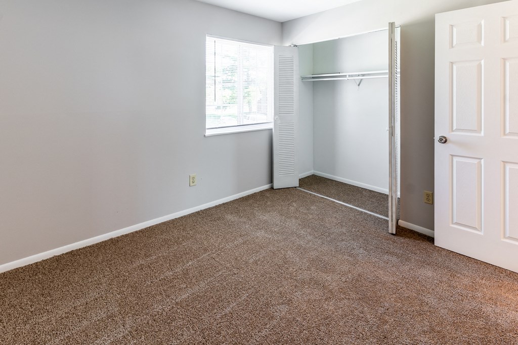 an empty room with carpet and a window and a closet at Pickwick Farms Apartments, Indianapolis, IN