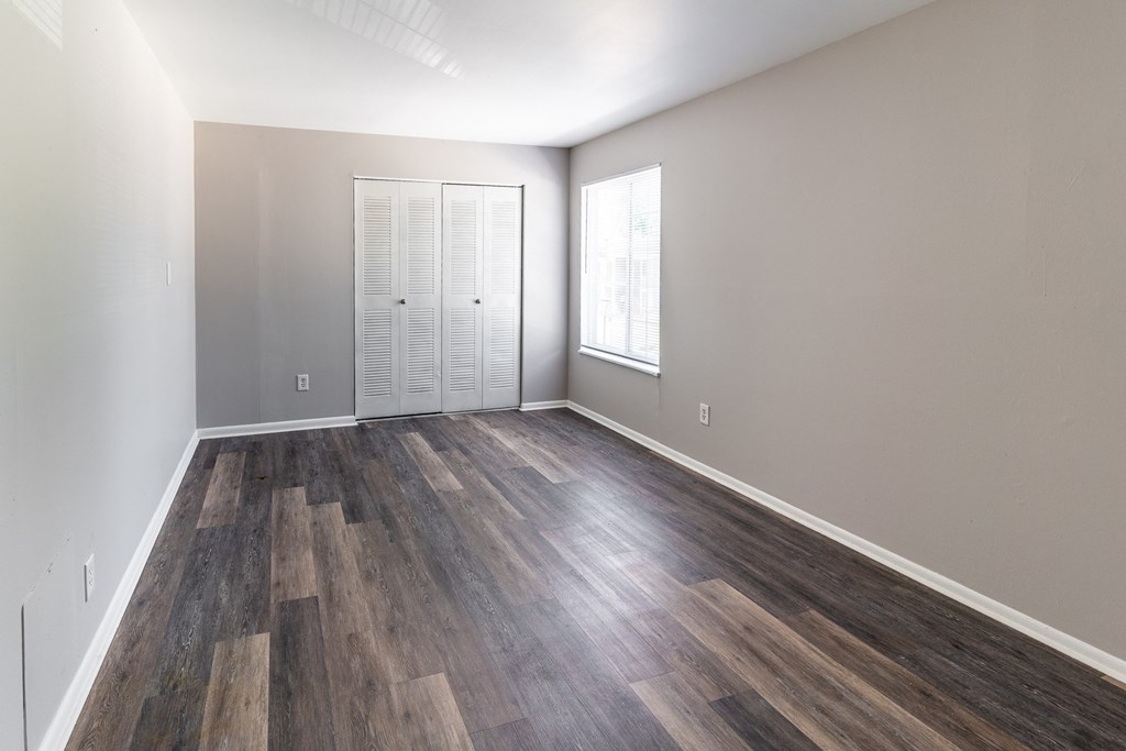 an empty living room with wood flooring and a window at Pickwick Farms Apartments, Indianapolis