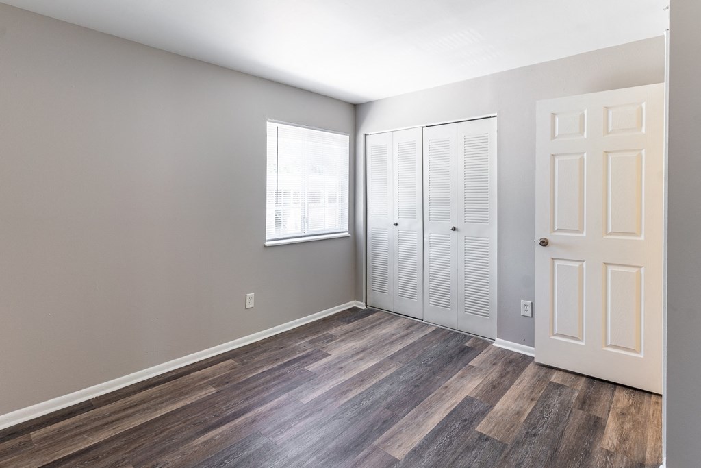 an empty room with wood flooring and white closet doors at Pickwick Farms Apartments, Indiana