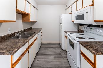 a kitchen with white appliances and granite counter tops at Walnut Creek Apartments, Indiana