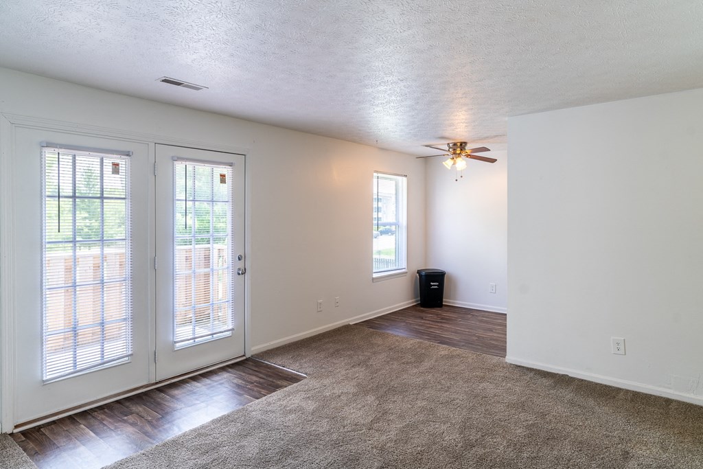 an empty living room with sliding glass doors and a ceiling fan at HUB of New Albany Apartments, New Albany