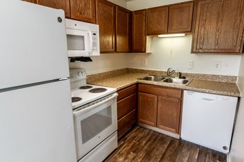 an empty kitchen with white appliances and wooden cabinets