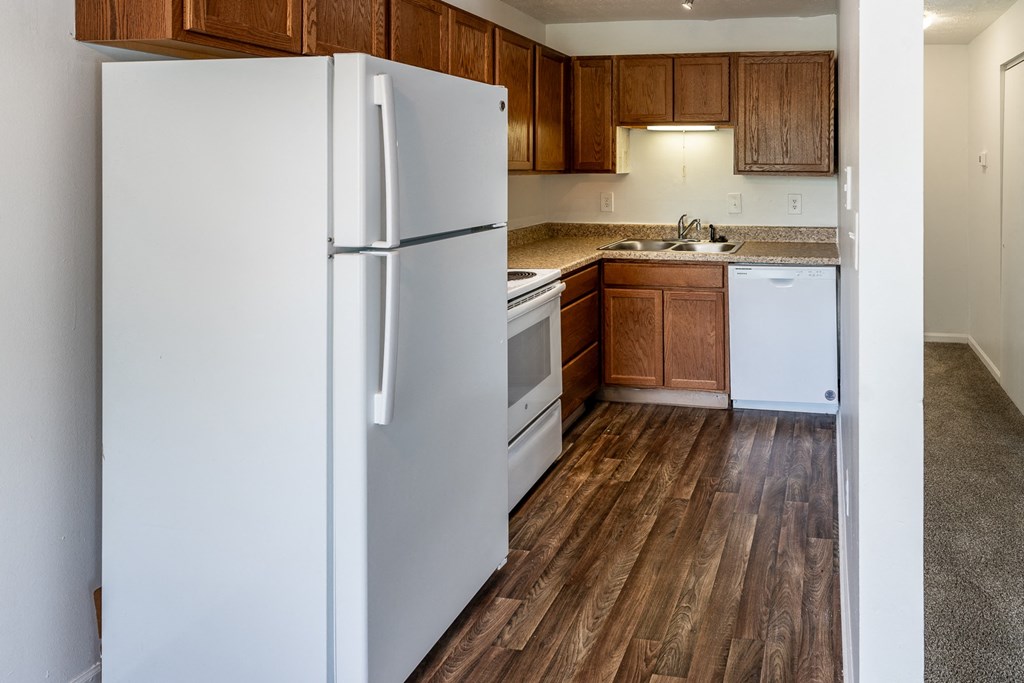 an empty kitchen with white appliances and wood floors at HUB of New Albany Apartments, Indiana