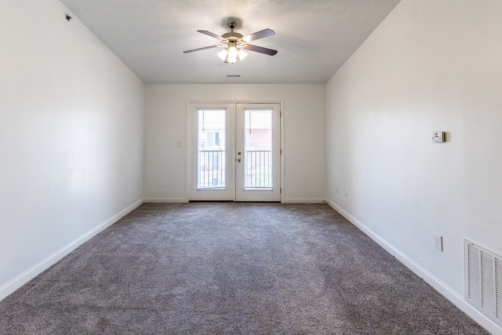 an empty living room with white walls and a ceiling fan at HUB of New Albany Apartments, New Albany