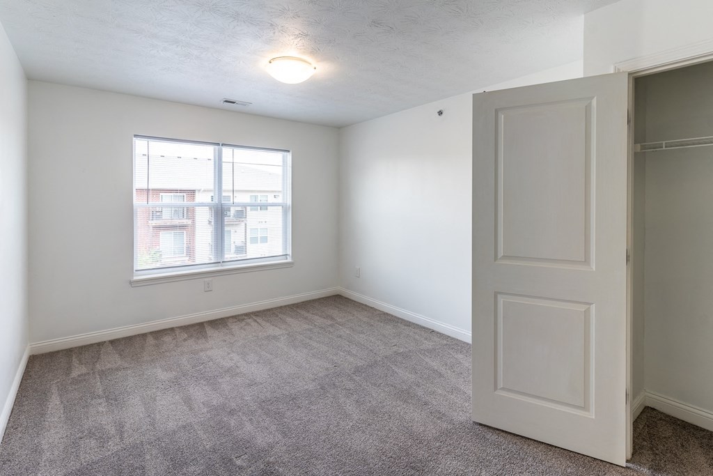 an empty bedroom with a closet and a window at HUB of New Albany Apartments, New Albany, IN, 47150