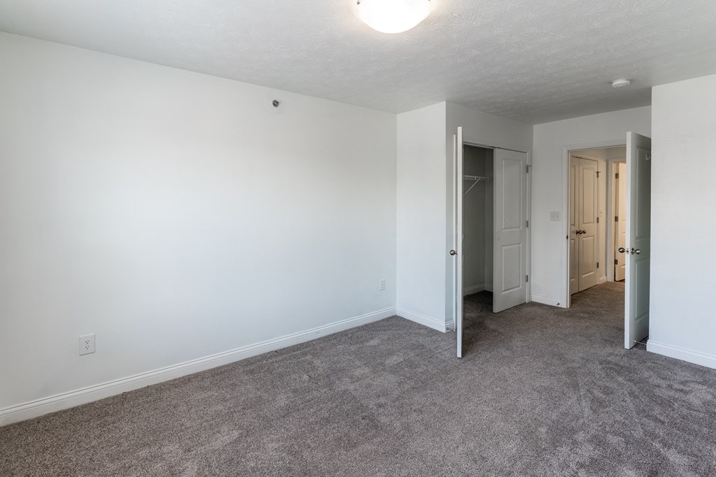 an empty living room with white walls and carpet at HUB of New Albany Apartments, New Albany, Indiana