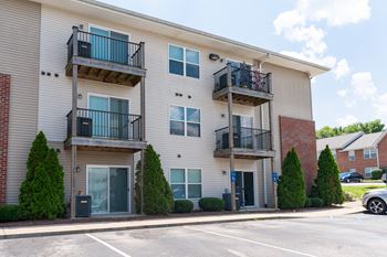 an apartment building with two balconies and a parking lot