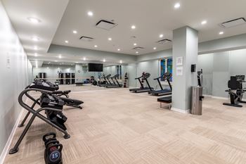 A gym with a variety of exercise equipment including treadmills, stationary bikes, and weight machines.