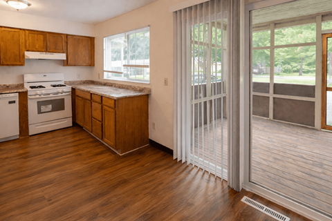 A kitchen with wooden cabinets and a white stove top oven.