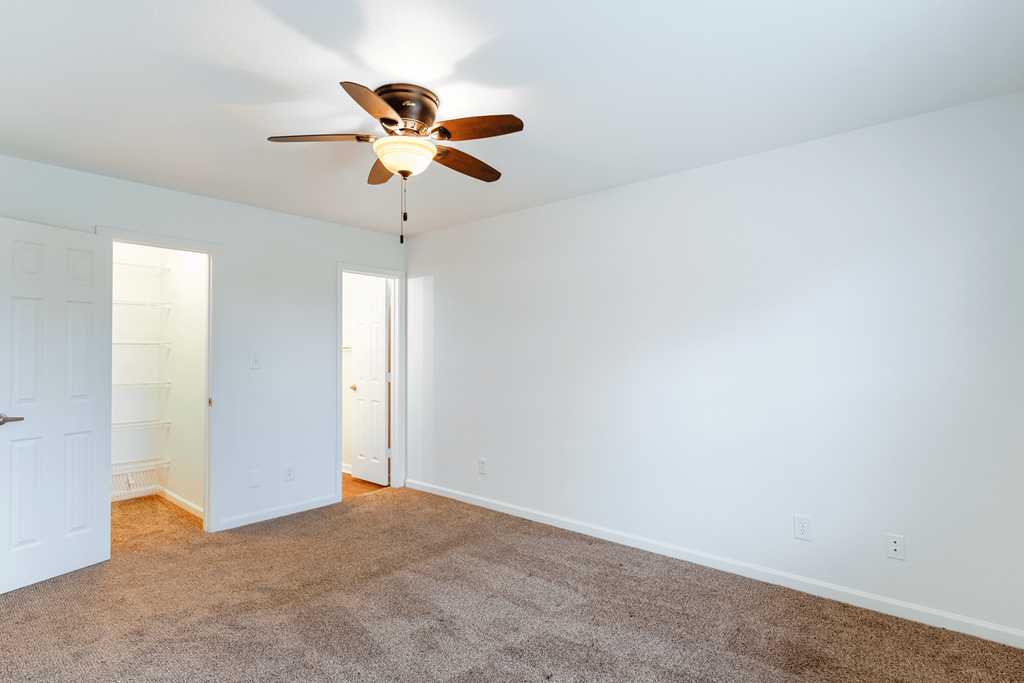 a living room with a ceiling fan and a carpet