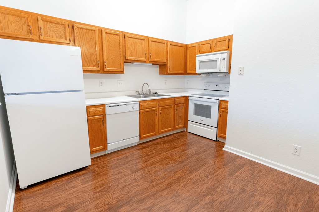 an empty kitchen with white appliances and wooden cabinets