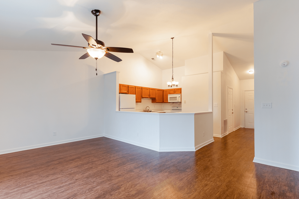 an empty living room with a ceiling fan and a kitchen at Barton Farms in Greenwood, IN 46143