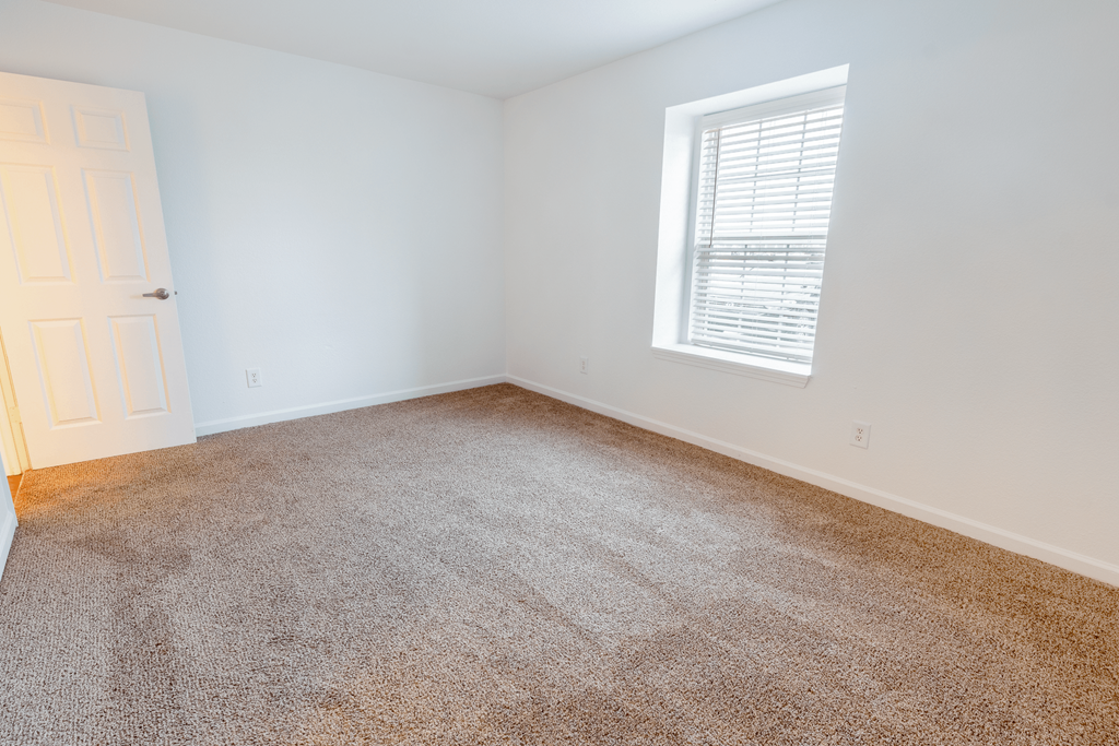 an empty room with carpet and a window