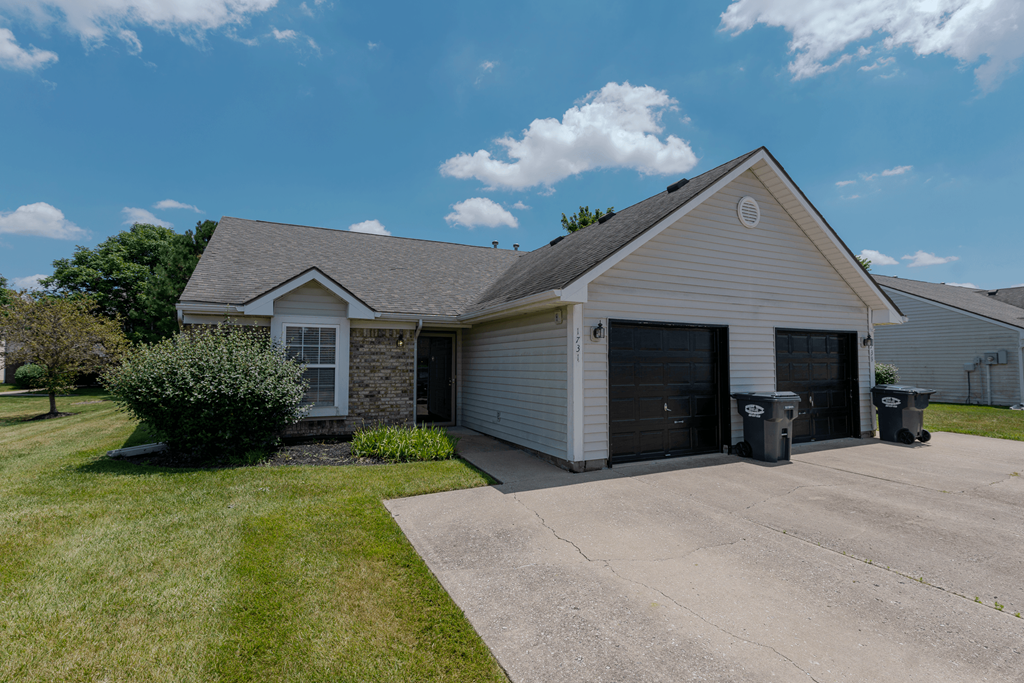 a white house with a driveway and a garage door at Barton Farms in Greenwood, IN 46143