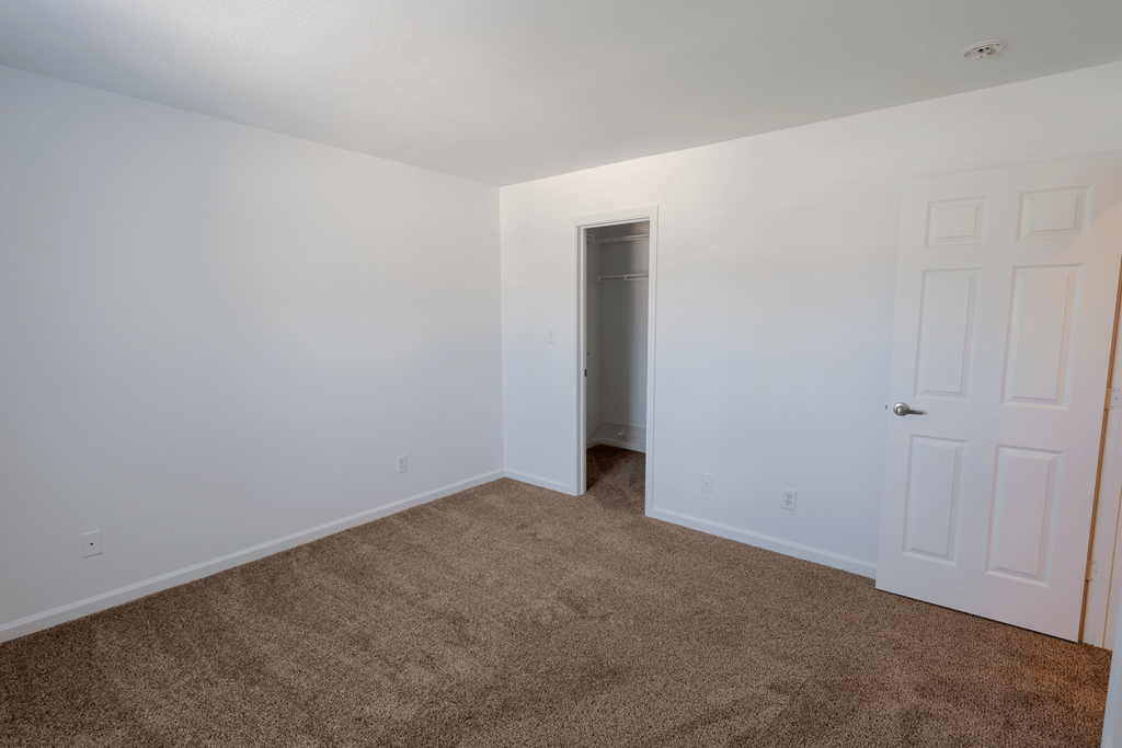 a bedroom with white walls and carpet and a door to a closet at Barton Farms in Greenwood, IN 46143