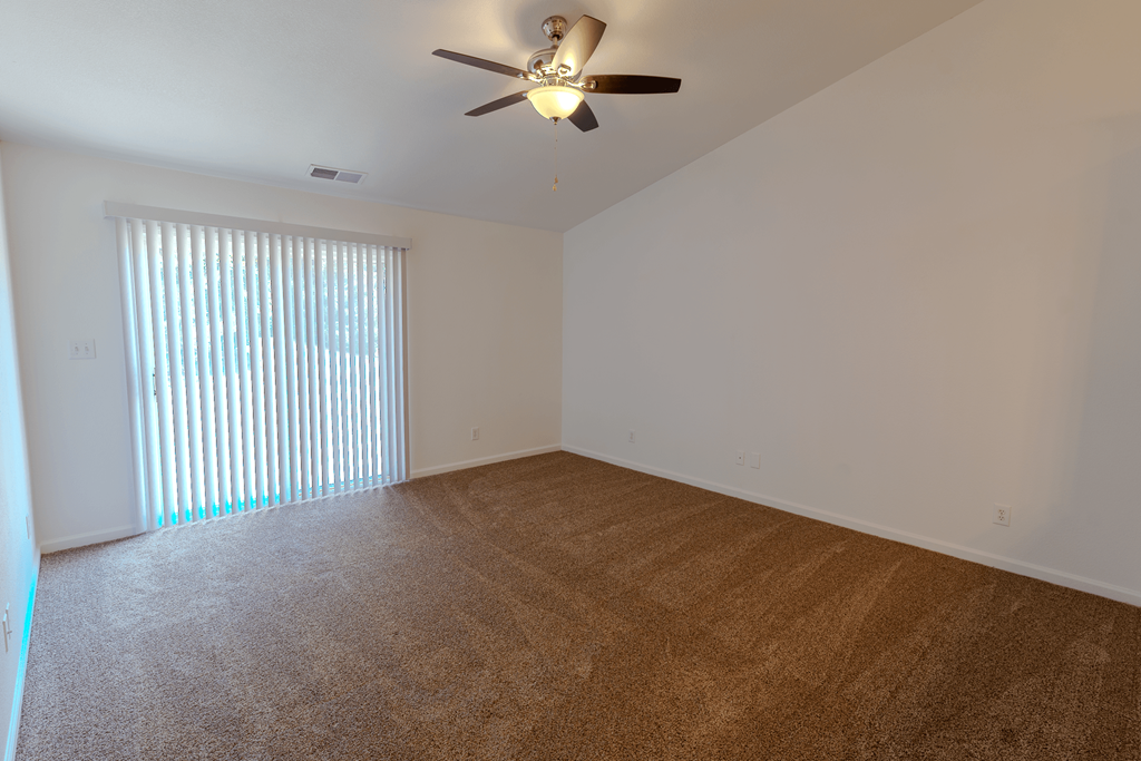 an empty living room with a large window and a ceiling fan at Barton Farms in Greenwood, IN 46143