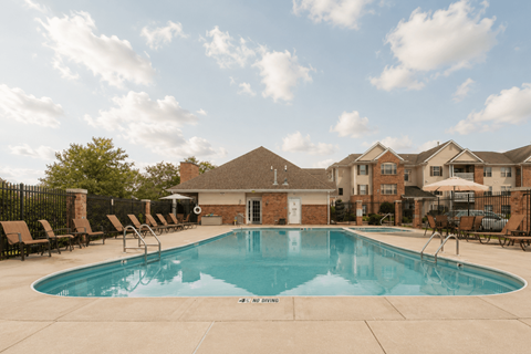 A large swimming pool surrounded by lounge chairs and a building in the background.