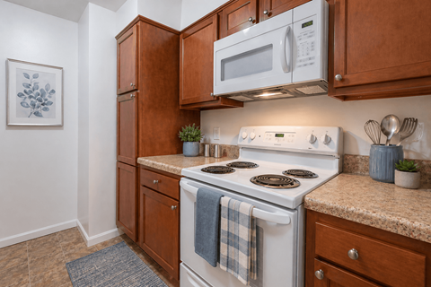 A kitchen with a white stove top oven and a white microwave above it.