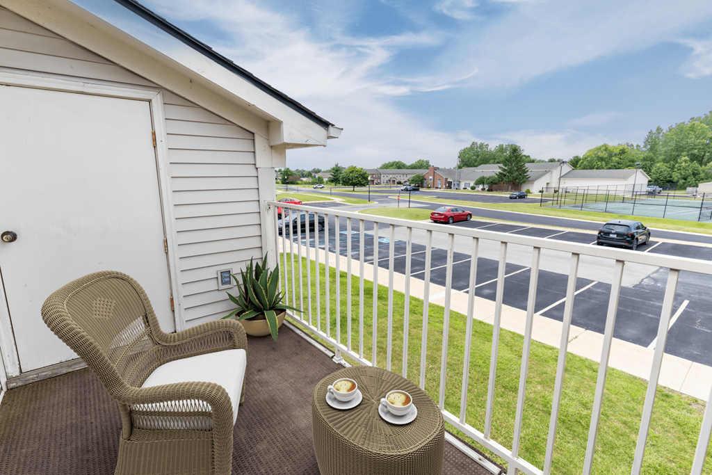 a balcony with two chairs and a table overlooking a parking lot at Walnut Creek Apartments, Kokomo, IN, 46902