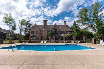 a swimming pool in front of a large brick house with a pool