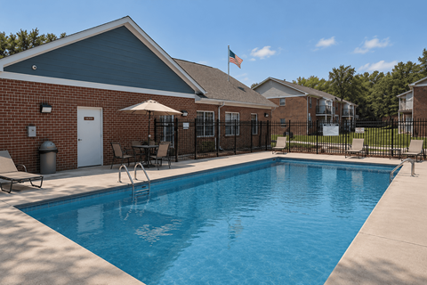 A pool in front of a brick building with a flag on top.