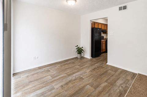A room with a wooden floor and a black refrigerator.